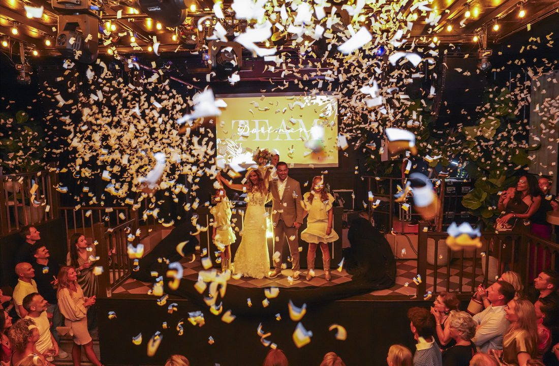Newly married couple and children surrounded by confetti during a wedding celebration