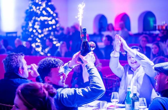 Guests celebrating with a sparkling bottle and sparkler during a dinner show