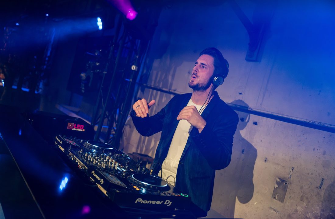 DJ behind professional equipment in blue and purple stage lighting