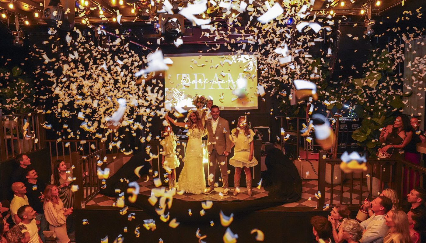 Newly married couple and children surrounded by confetti during a wedding celebration