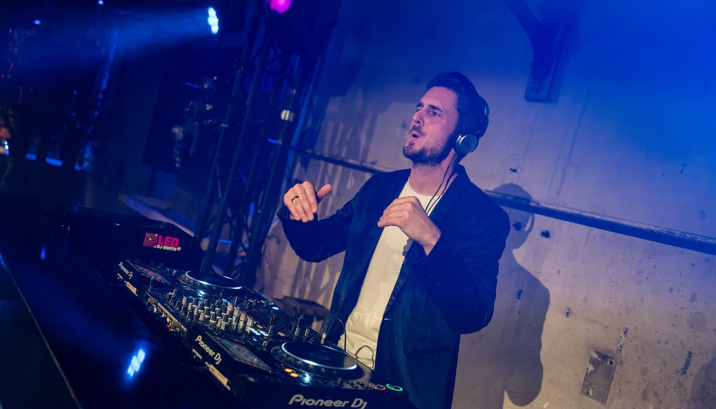 DJ behind professional equipment in blue and purple stage lighting