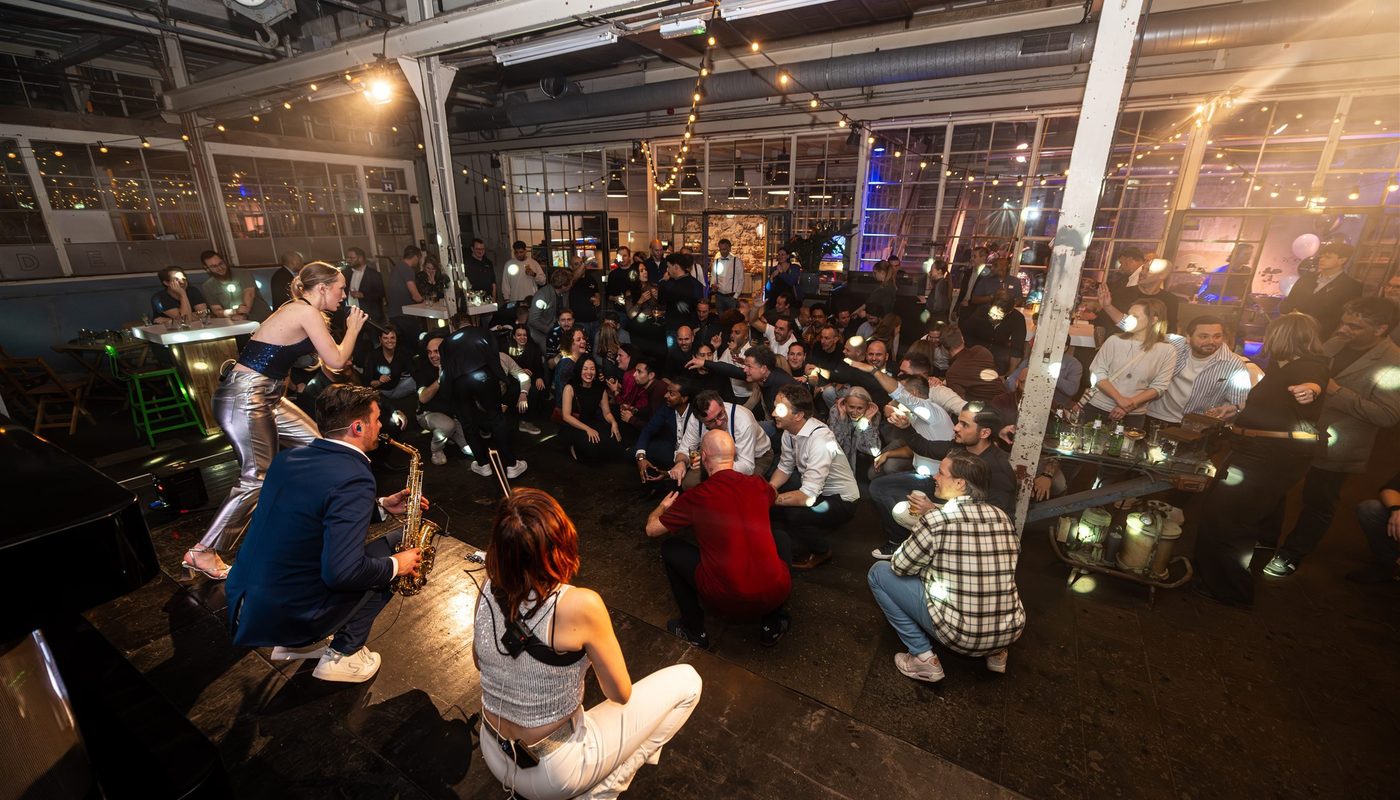 Singer and saxophonist performing among guests at an event